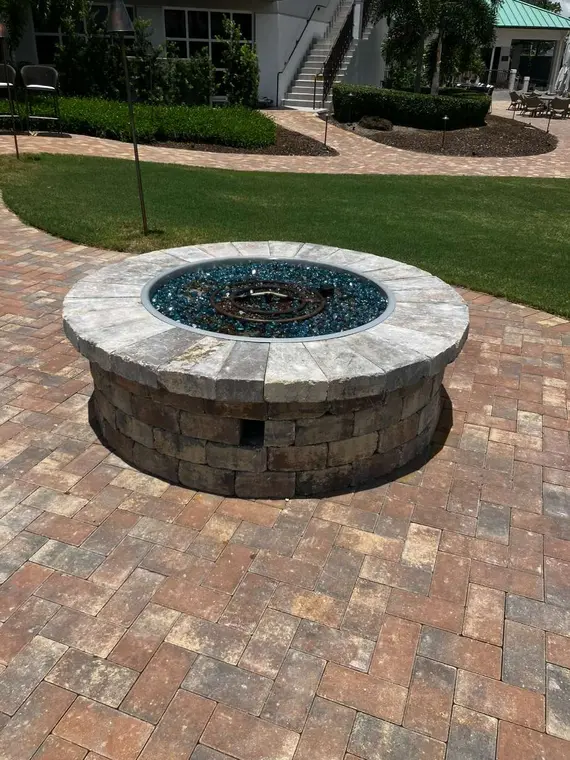 Circular masonry fire pit centered on a brick paver patio